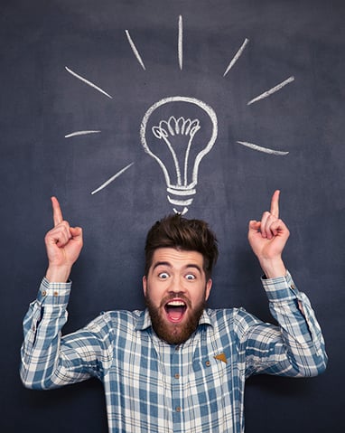 Amazed funny young man with tousled hair pointing up and having an idea standing over blackboard background