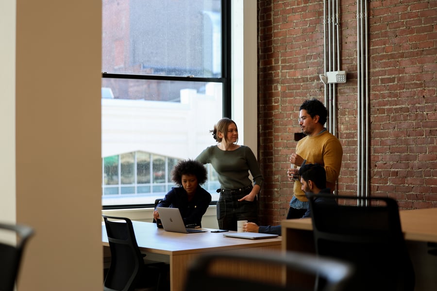 A cozy individual workspace nook at Workbar Somerville featuring an exposed brick wall and a desk by a window.